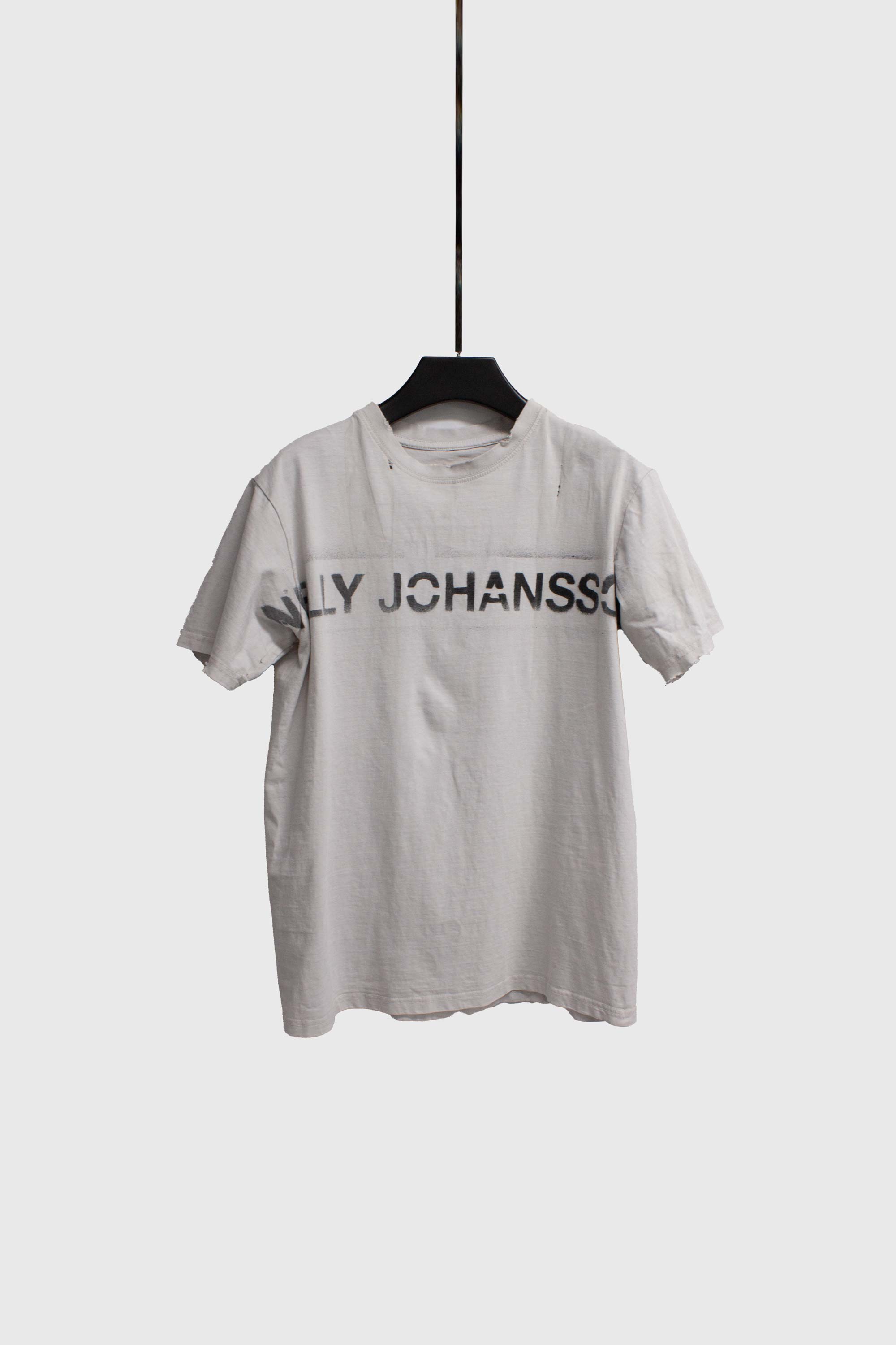 Single white t-shirt on black hanger showing front with NELLY JOHANSSON print
