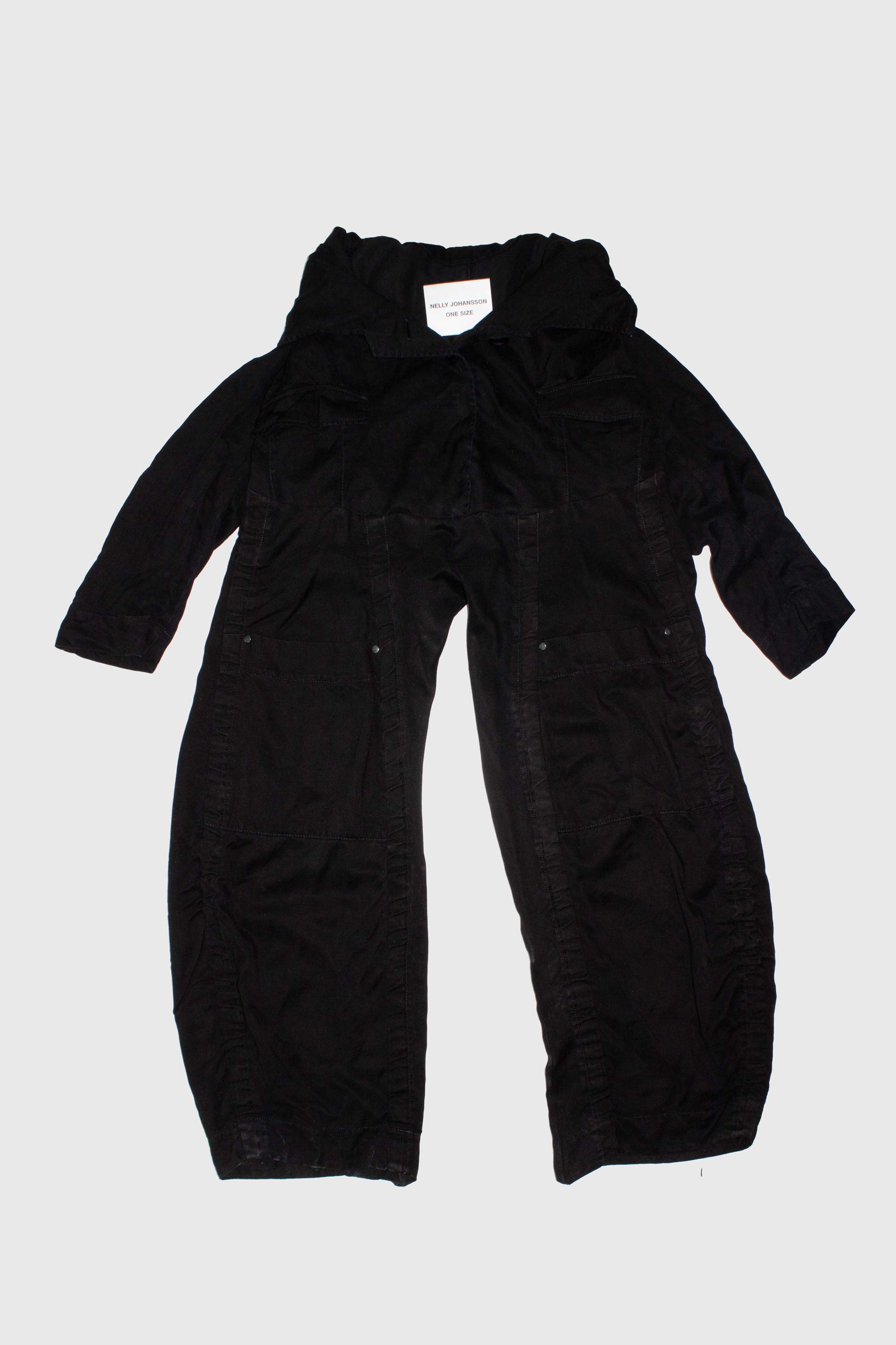 Black deconstructed trousers laid flat showing blazer waist construction with sleeves and button details