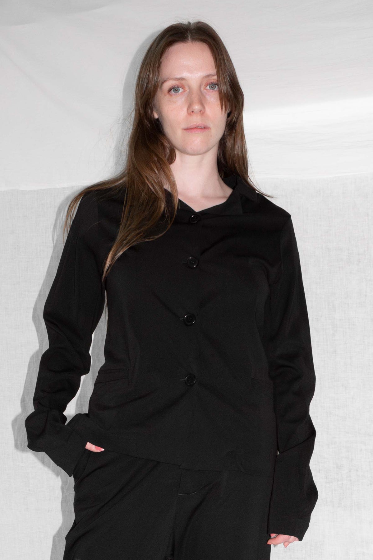 Model wearing black tailored jacket with matching trousers, showing fitted silhouette and button closure – Tailored Suit Jacket by NELLY JOHANSSON