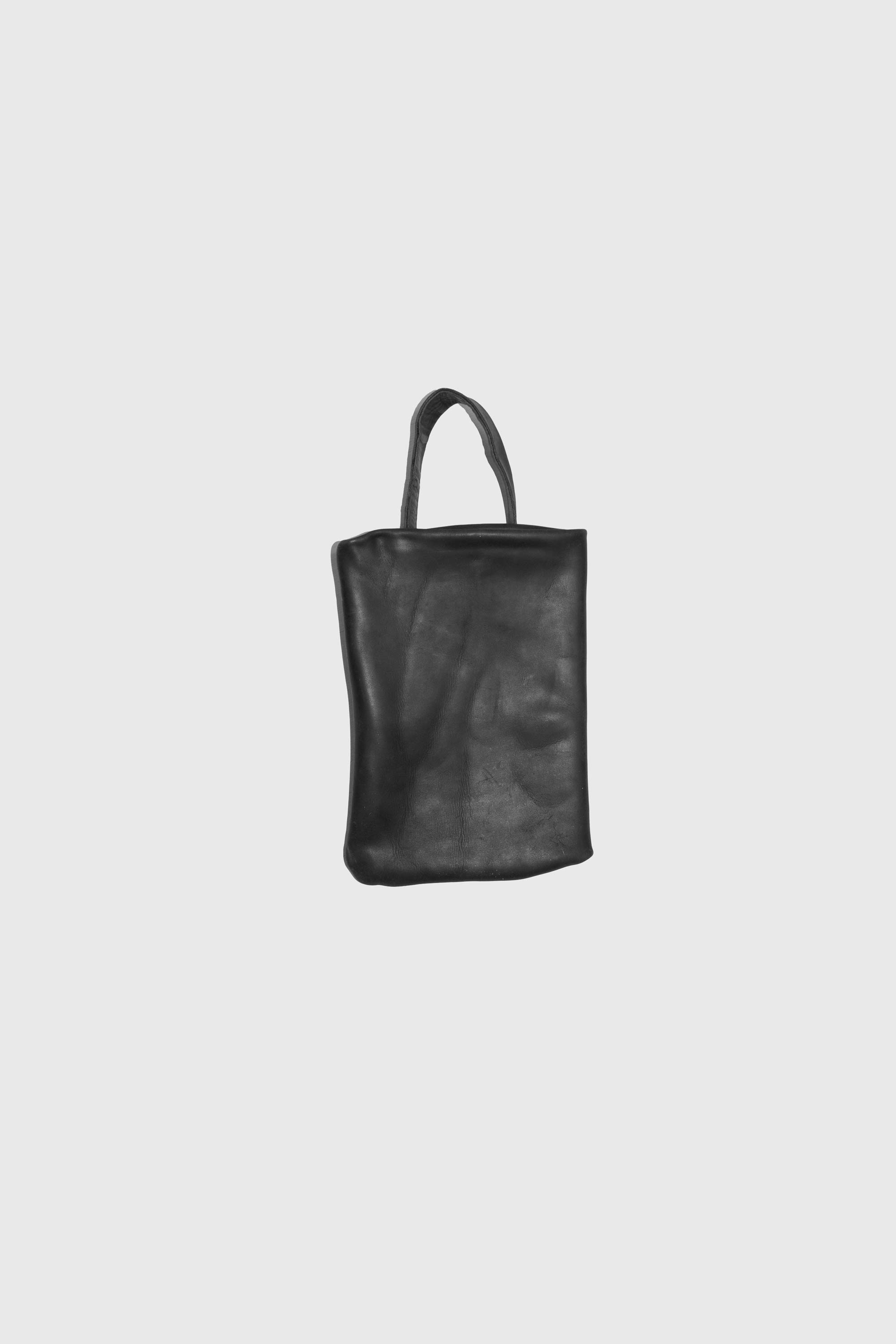 Black rectangular leather tote photographed at angle showing thick unstructured body