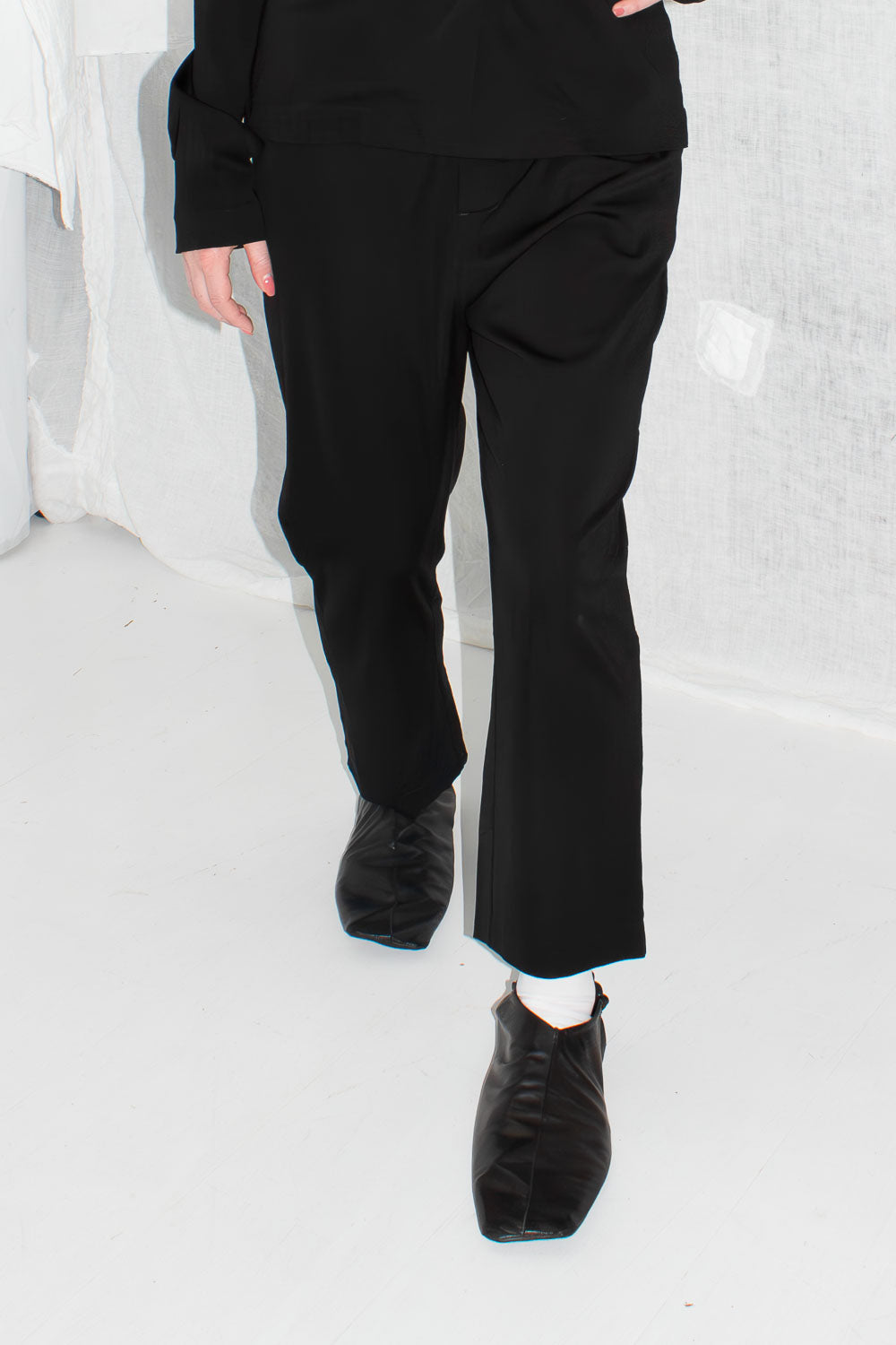 Black tapered trousers styled on model with matching blazer and boots