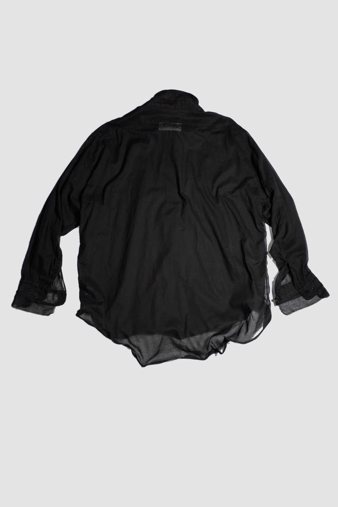 Back view of black cotton shirt laid flat, showing oversized construction and extended length