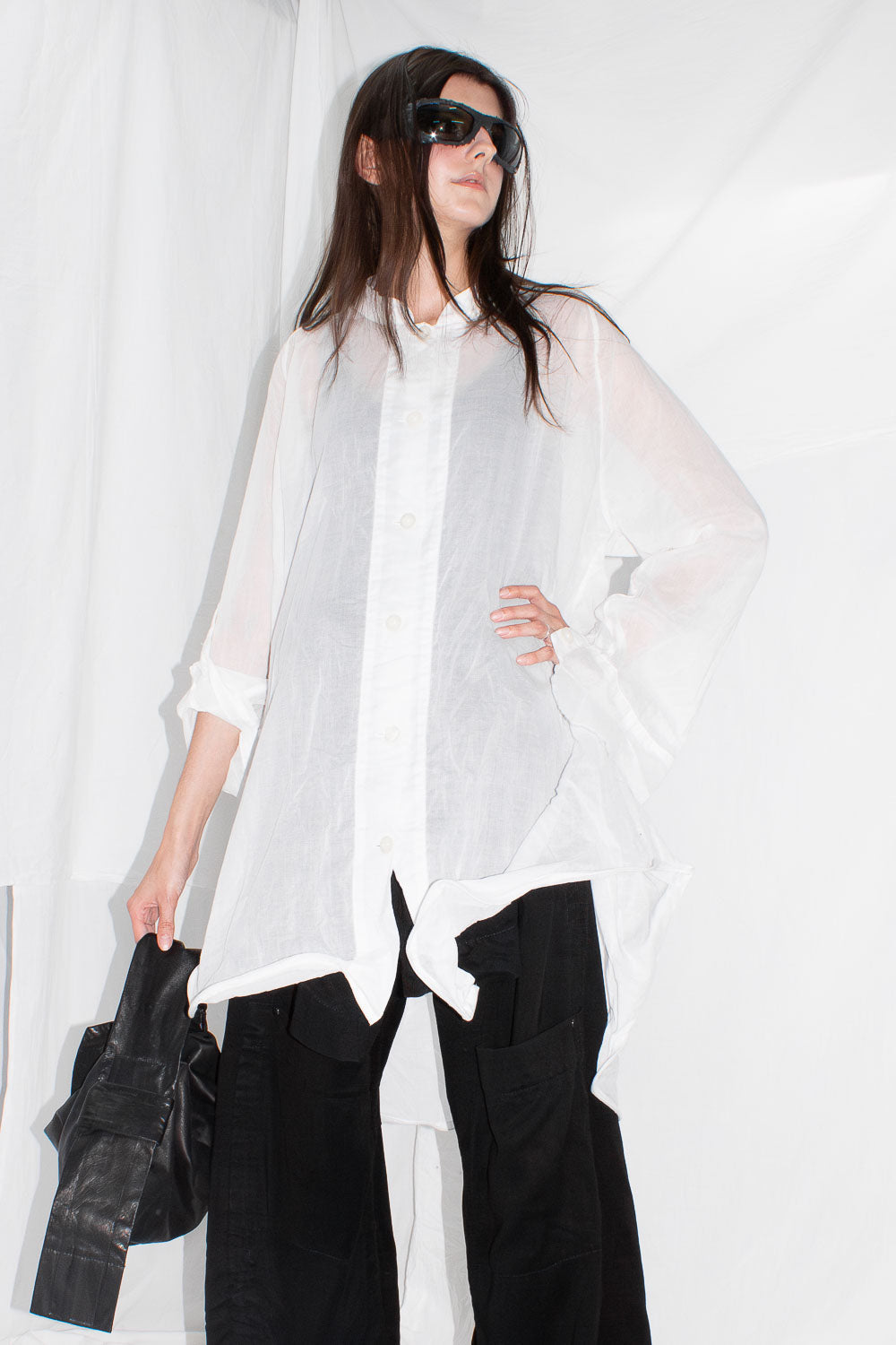 Front view of model in white sculptural shirt with sunglasses and draped shoulders