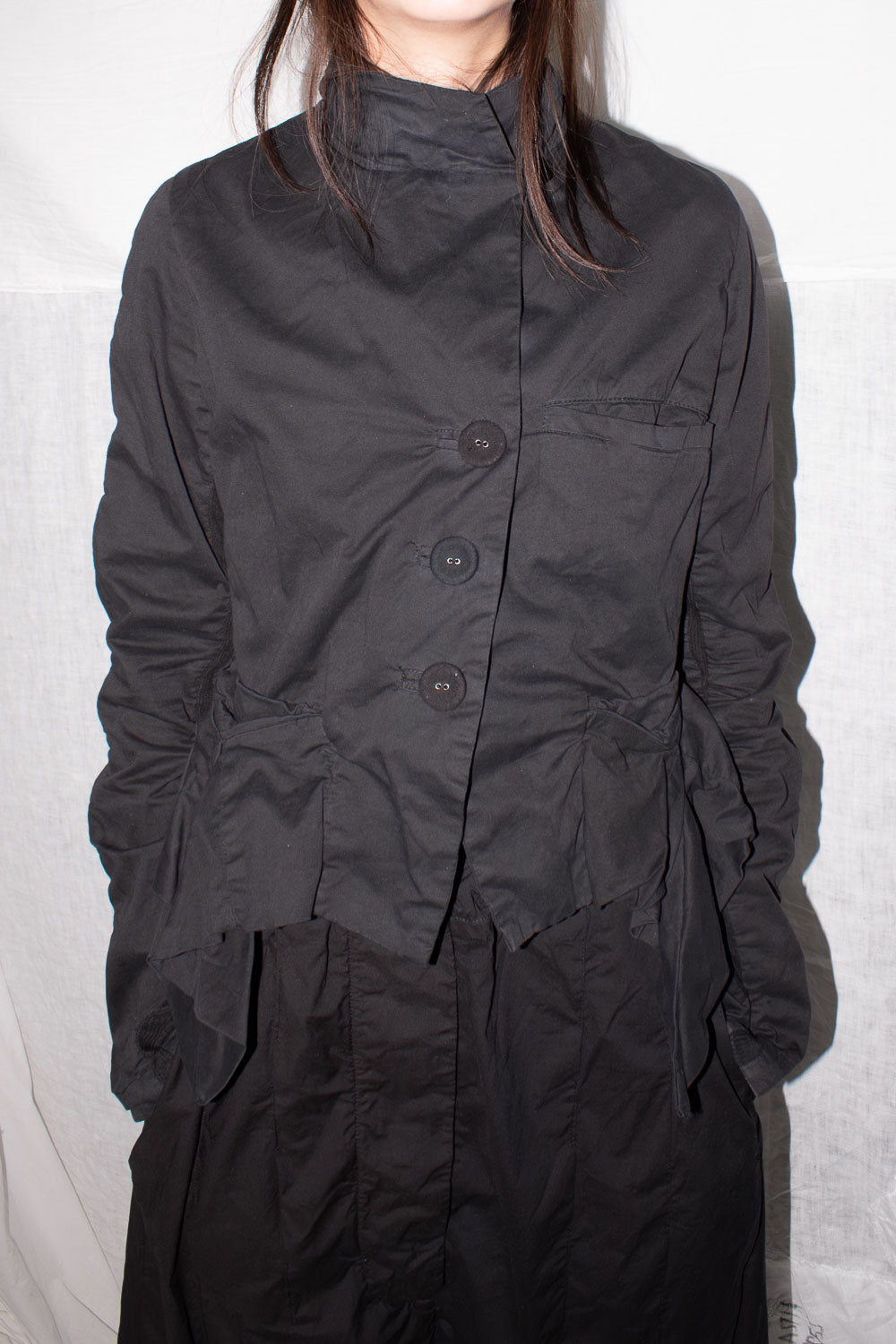 Detail view of high collar and three button closure with visible ruched construction