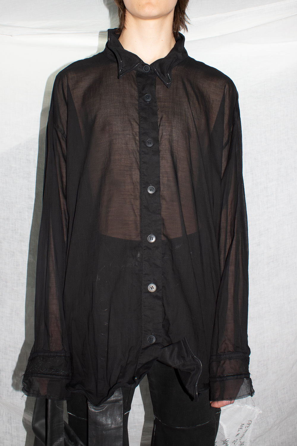 Black sheer cotton shirt worn on model, showing oversized silhouette and semi-transparent fabric