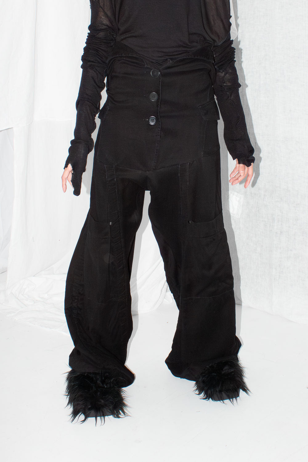 Close-up detail of three-button waist closure and pocket construction on black lyocell trousers