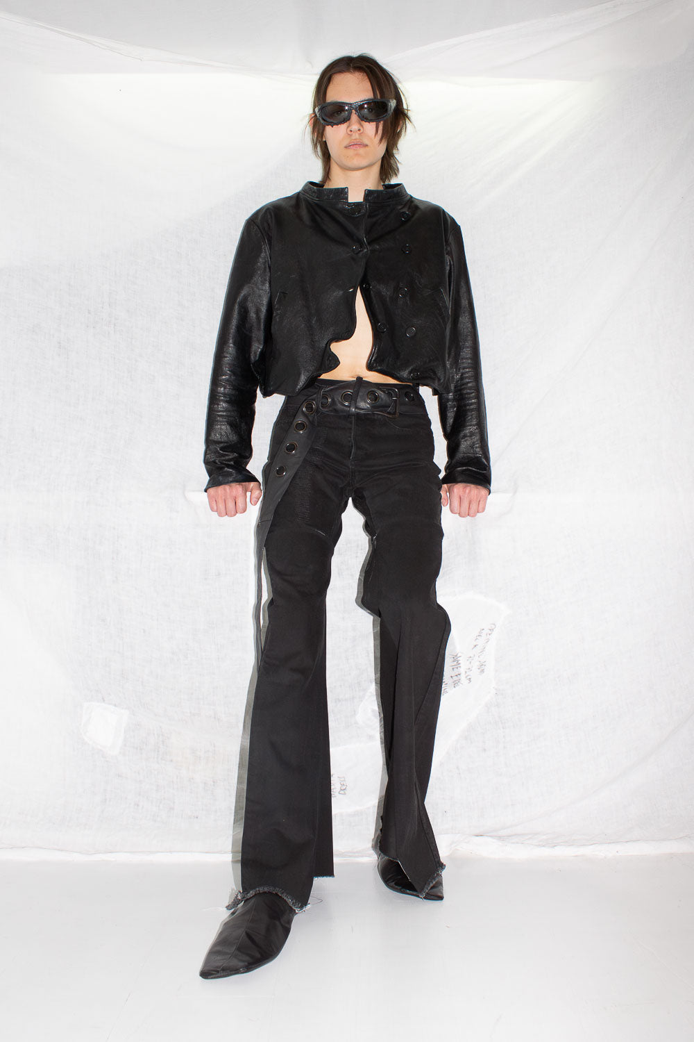 Full body shot of model in black leather jacket paired with matching leather pants and pointed boots