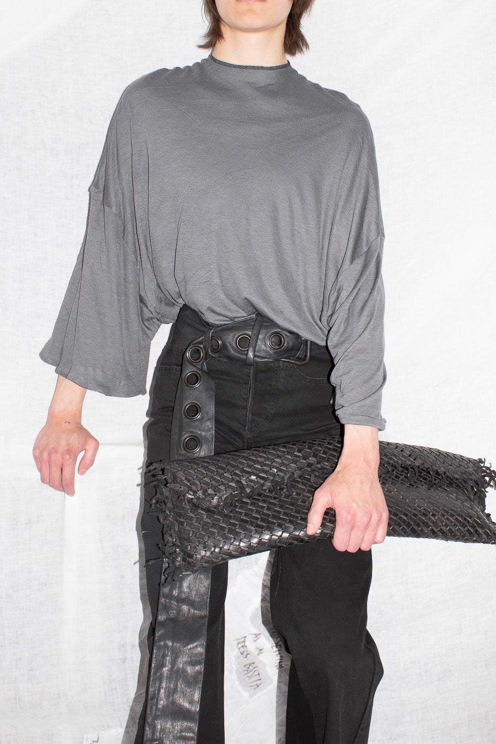 Model wearing grey oversized t-shirt with black leather trousers, hands at sides