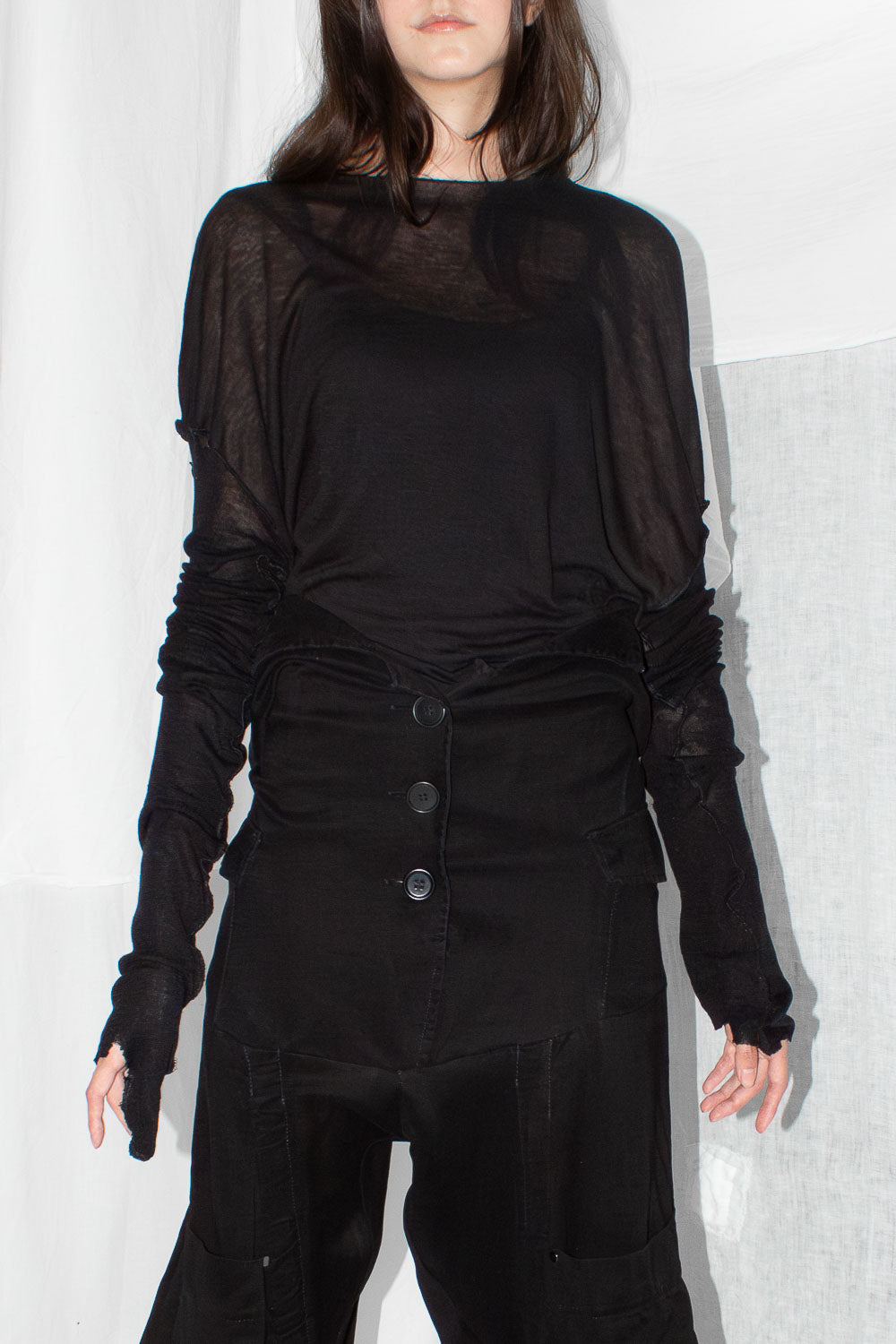 Model wearing black silk top with extended sleeves styled with high-waisted trousers