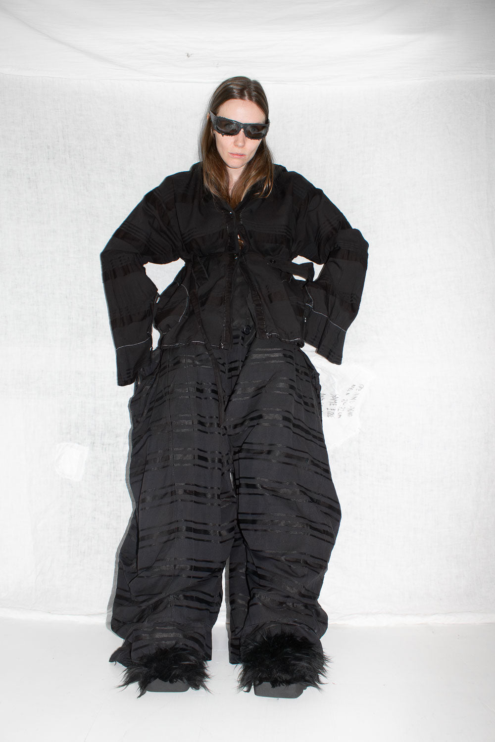 Model wearing black shirt with oversized patch pockets and contrast topstitching, styled with dark sunglasses