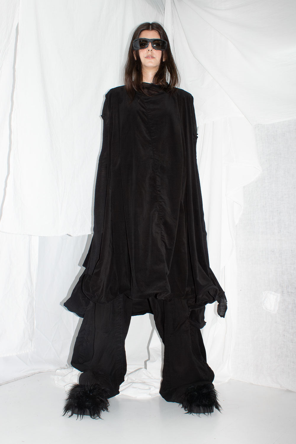 Front view of model wearing black velvet dress with sunglasses and extended sleeves