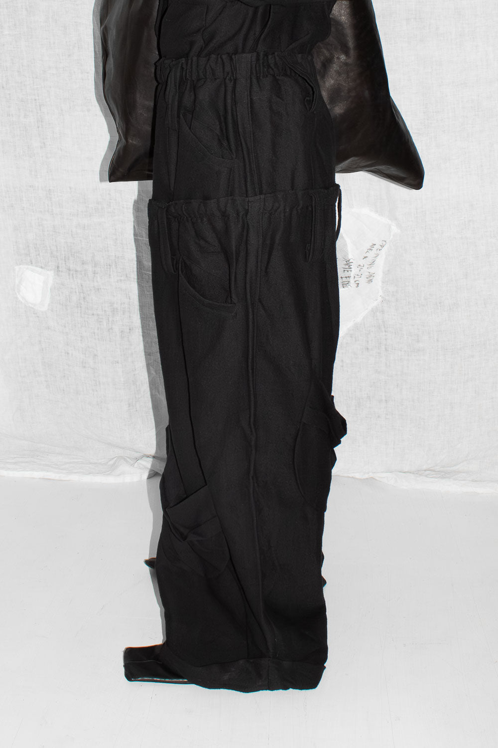 Side detail view of black trousers showing cargo pocket placement and folded hem construction