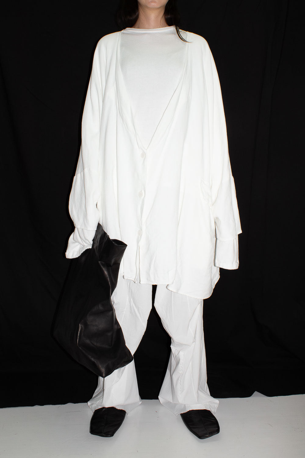 Front view of model in white cardigan showing oversized proportions and dropped shoulders