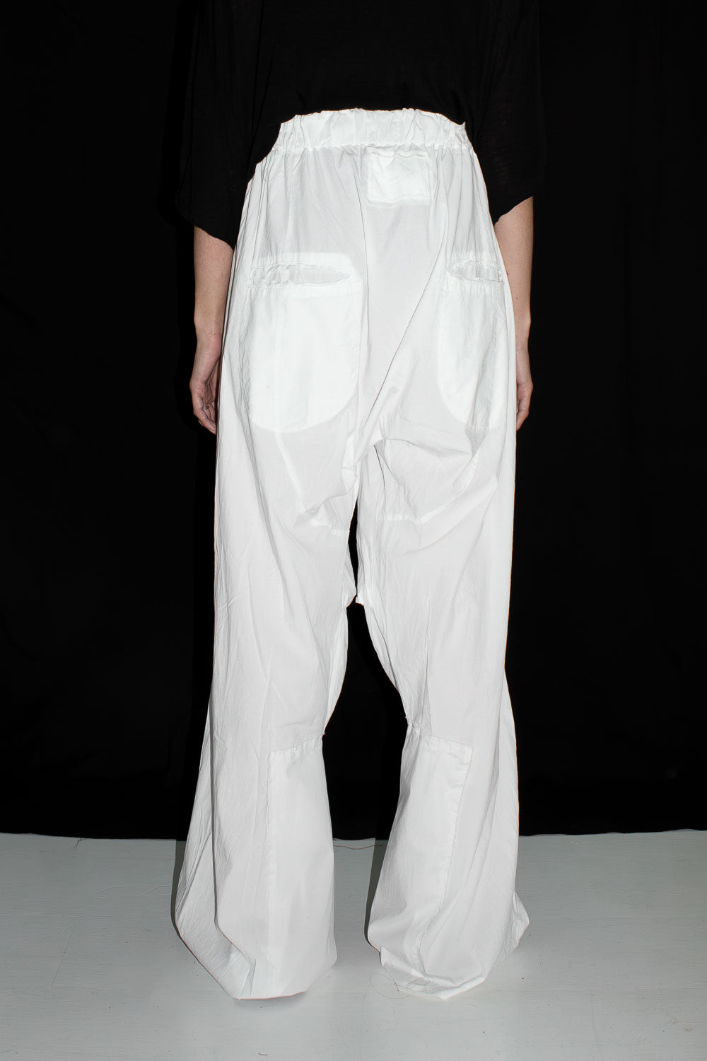 Back view of white loose slacks on model showing patched panels and pockets