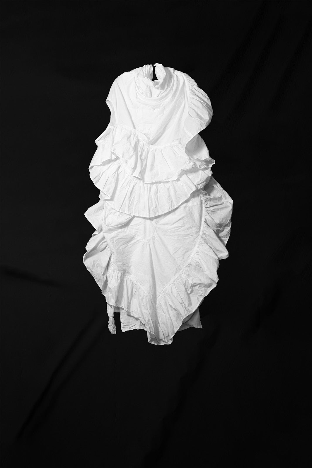 White multi-layered ruffle dress with tie collar detail shown against black background flat lay