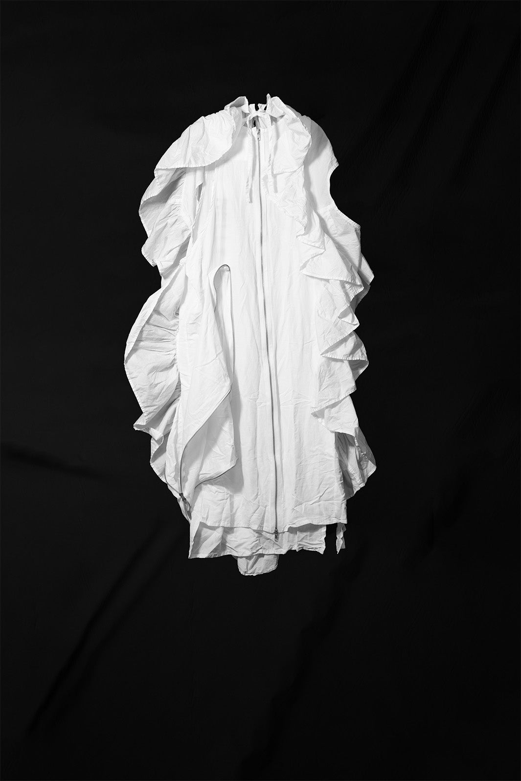 White ruffle dress with asymmetric construction and raw edges laid flat showing full silhouette