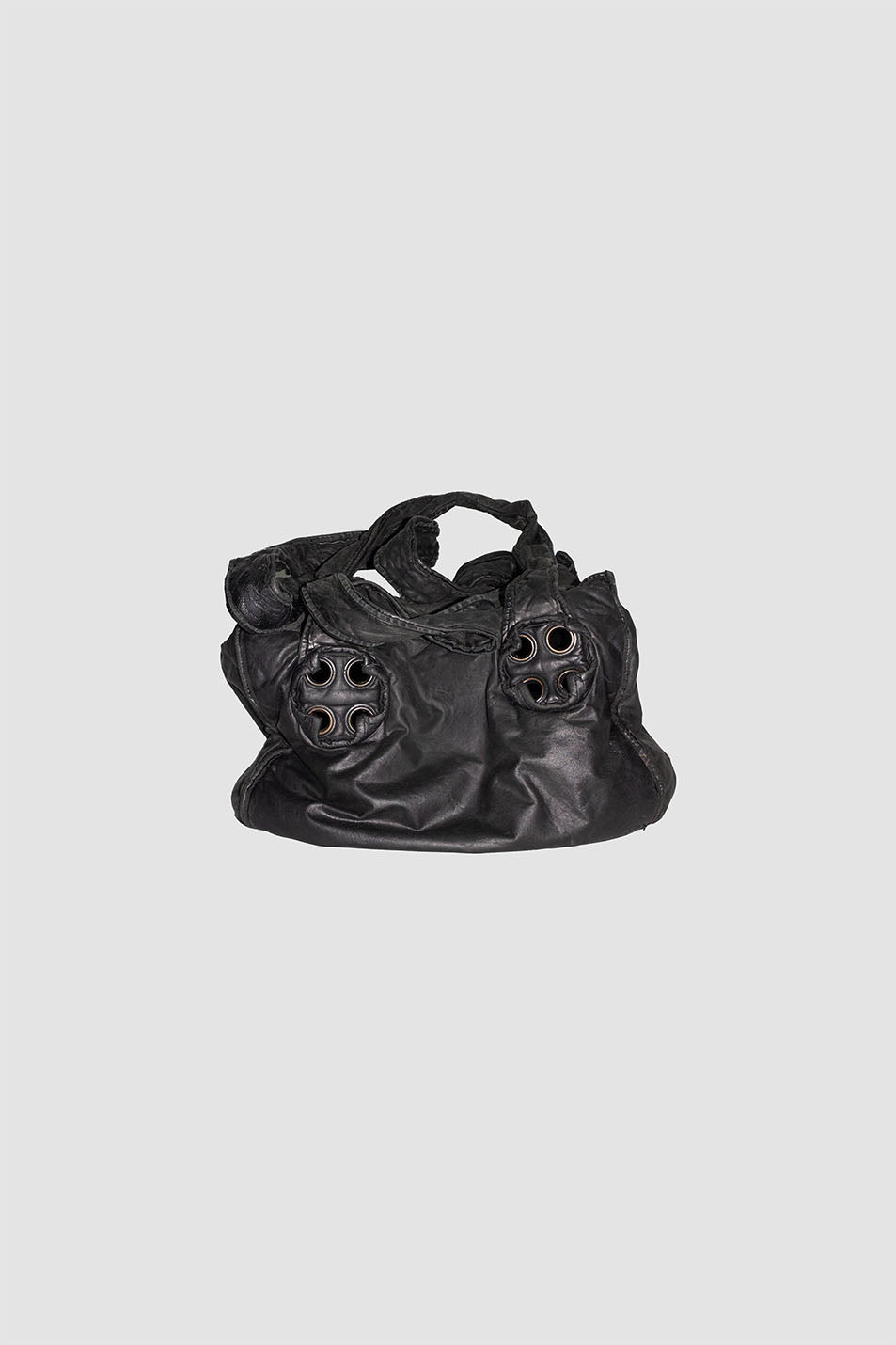 Black leather shoulder bag with braided handles and four metal eyelets on front, studio shot on grey background