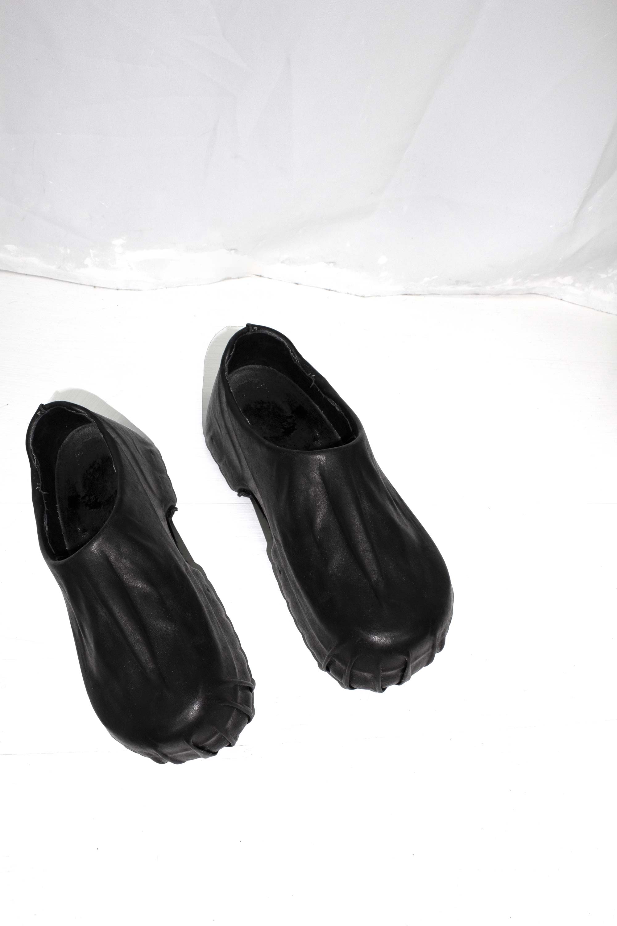 Black leather wrapped clogs photographed from above on white background