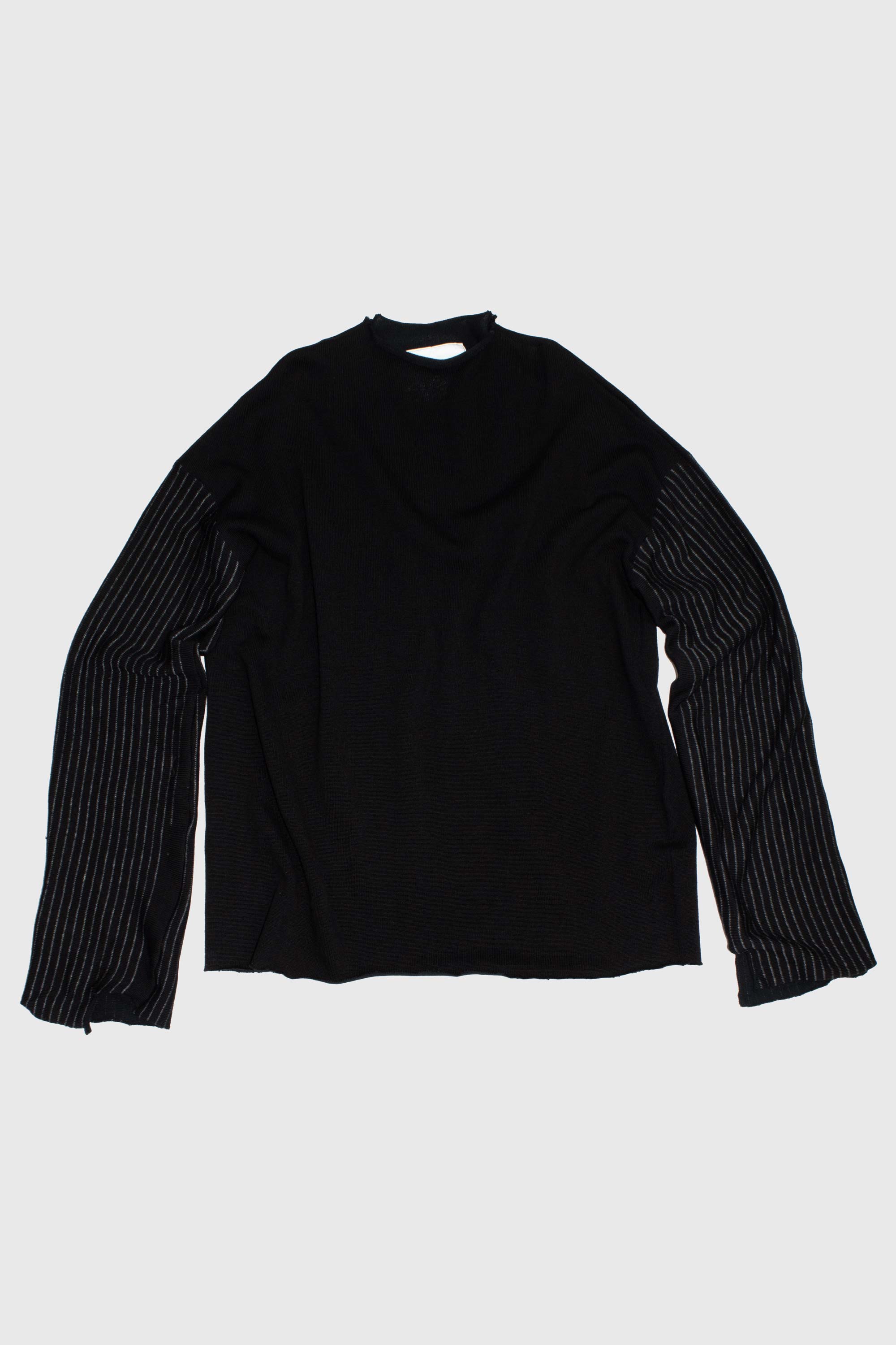 Back view of black knit sweater showing raw hem detail and striped sleeve construction