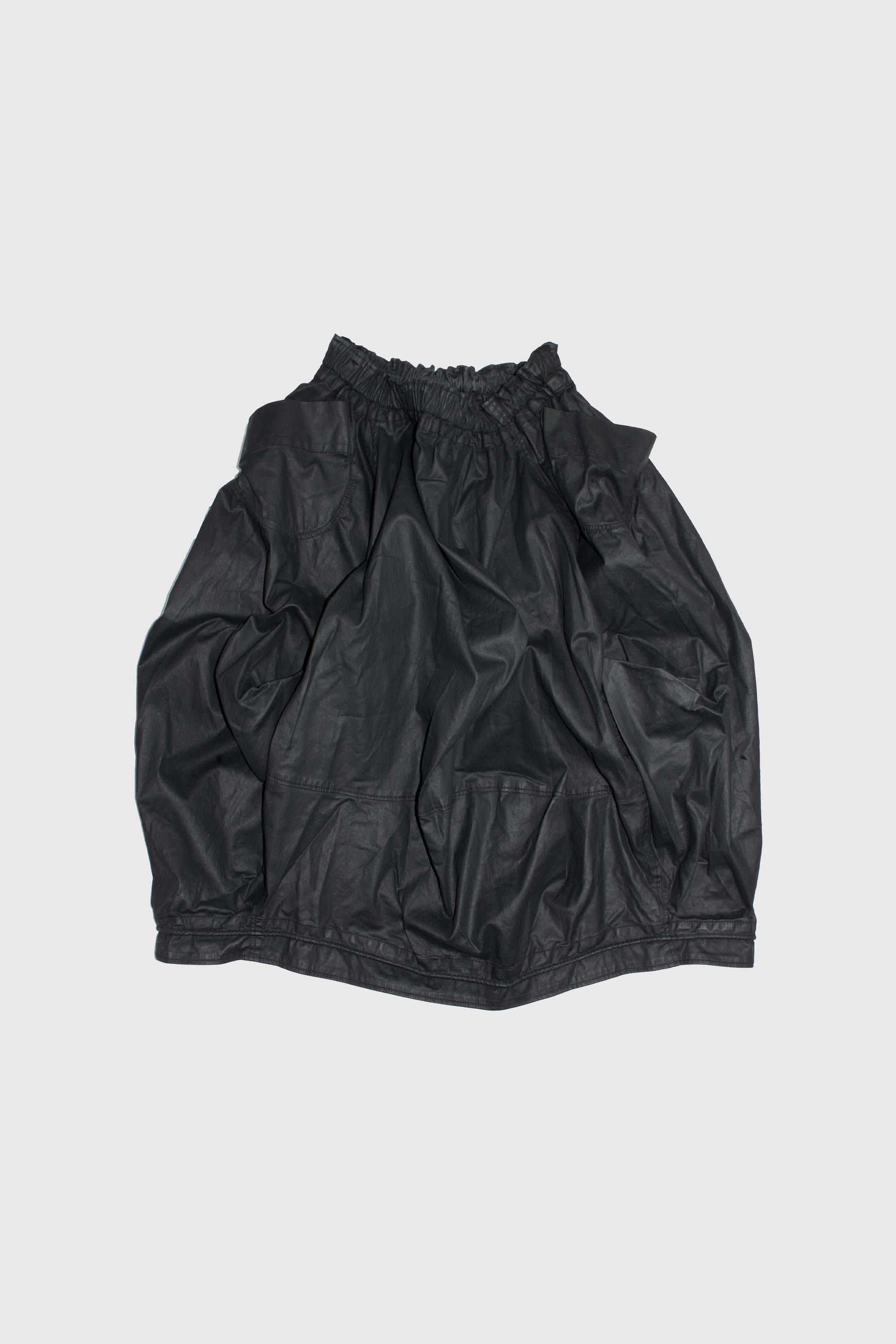 Black cotton top laid flat showing gathered elasticized neckline and voluminous silhouette