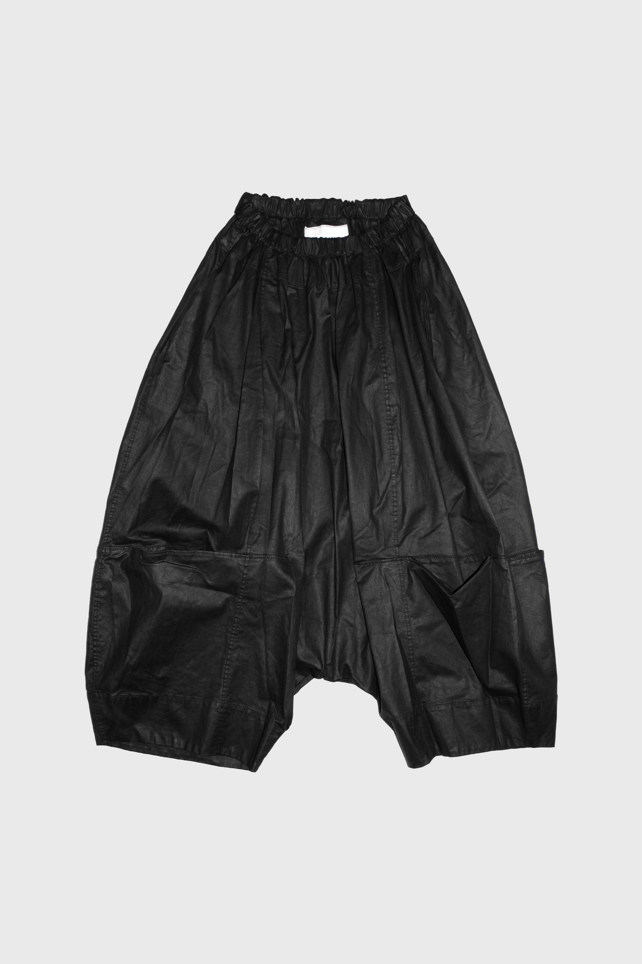 Black cropped trousers with elasticated waist and drop crotch silhouette on white background