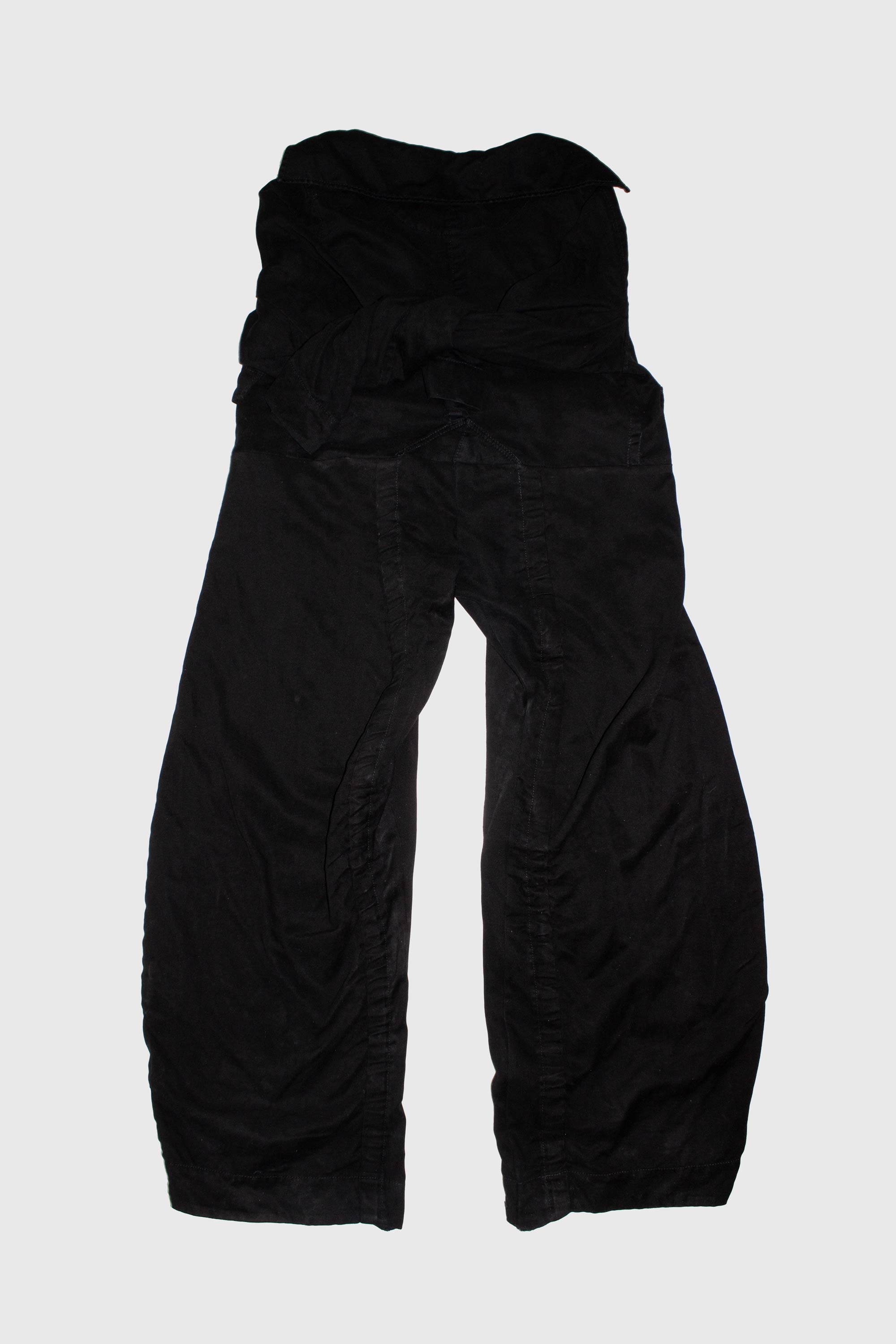 Black deconstructed trousers folded showing fabric texture and construction details