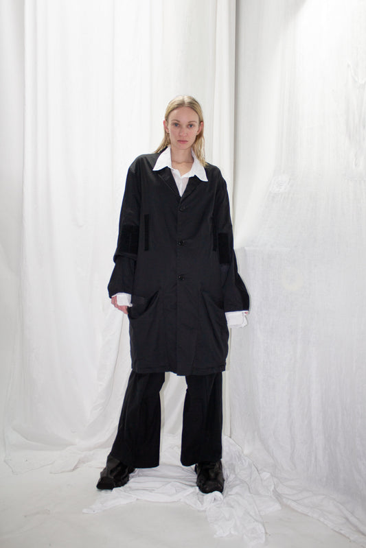 NELLY JOHANSSON 2023–24 collection: long black jacket with white collar over black trousers 19
