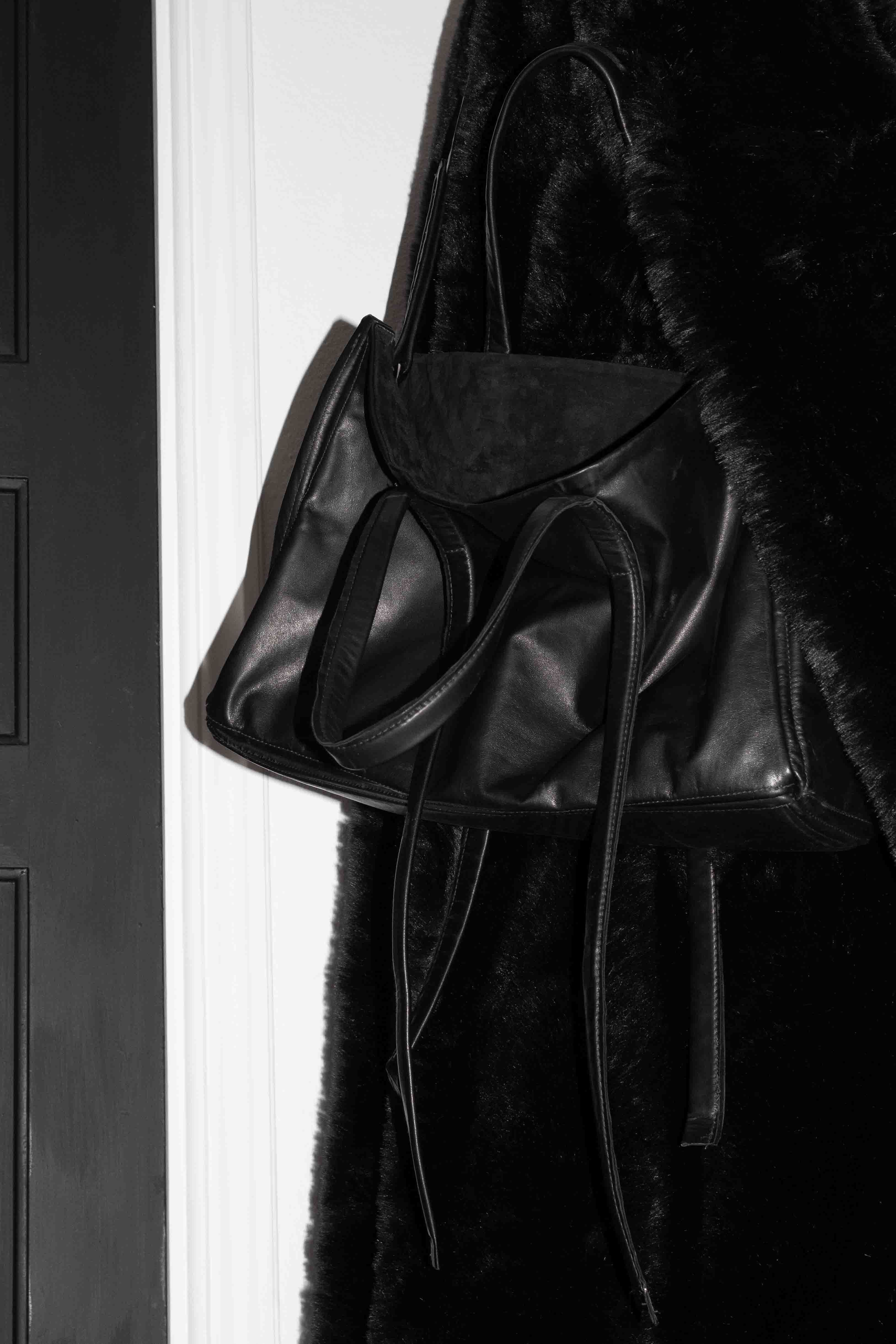 Horse leather tote bag worn on shoulder against black coat showing strap length and drape