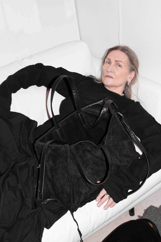 Model in black outfit holding horse leather tote bag, demonstrating scale and proportions 1