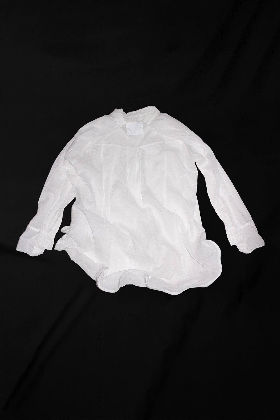 White shirt back view on black background displaying wire-sculpted hem construction