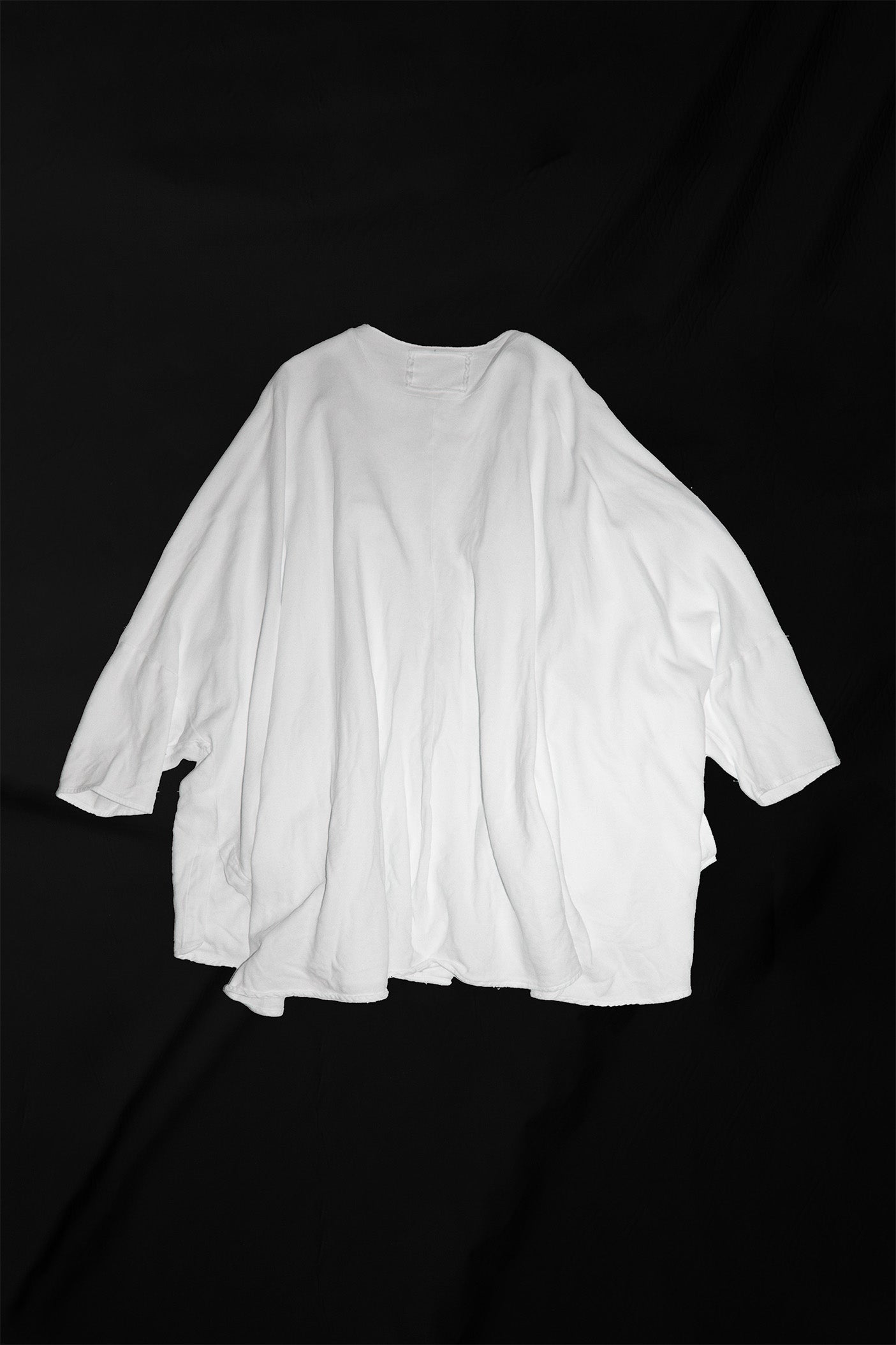 White cardigan laid flat on back showing relaxed fit and three-quarter length sleeves