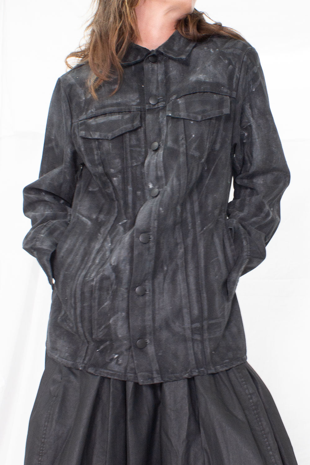 Close-up detail of chest pockets and snap button closure on waxed denim jacket worn by model