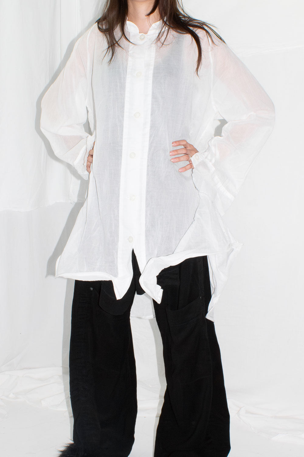 Model facing forward in white shirt with hands on hips showing oversized fit