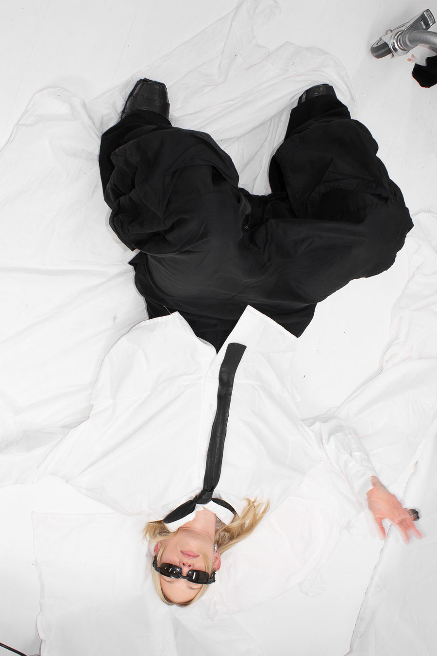 NELLY JOHANSSON 2024–25 collection: sculptural black bow bag, model lying on white sheets