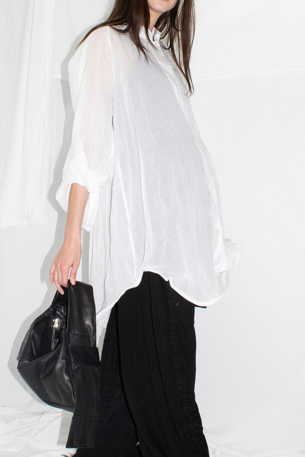Side view showing white shirt's voluminous silhouette and deconstructed cuffs