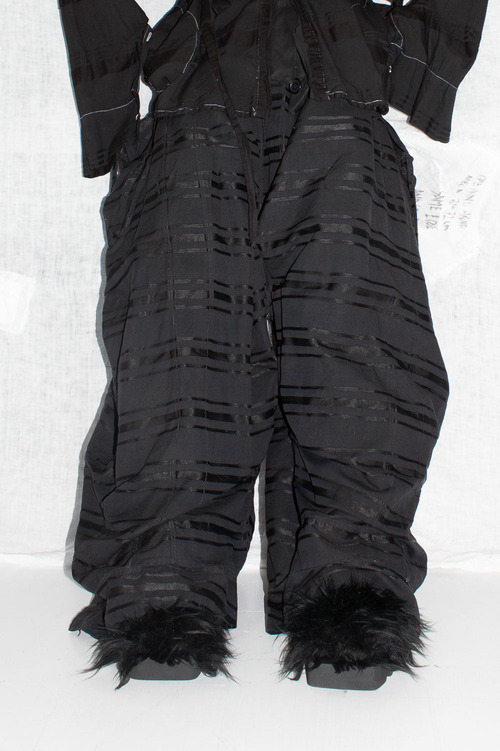Model wearing black striped trousers with fuzzy slippers showing wide leg proportion and gathered texture detail