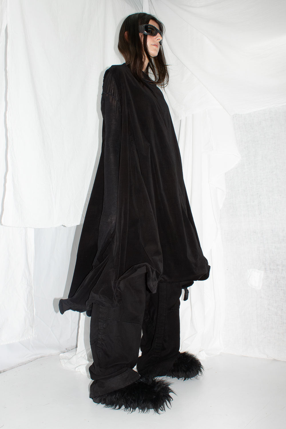 Side profile view of black dress with dramatic A-line silhouette and structured hem details