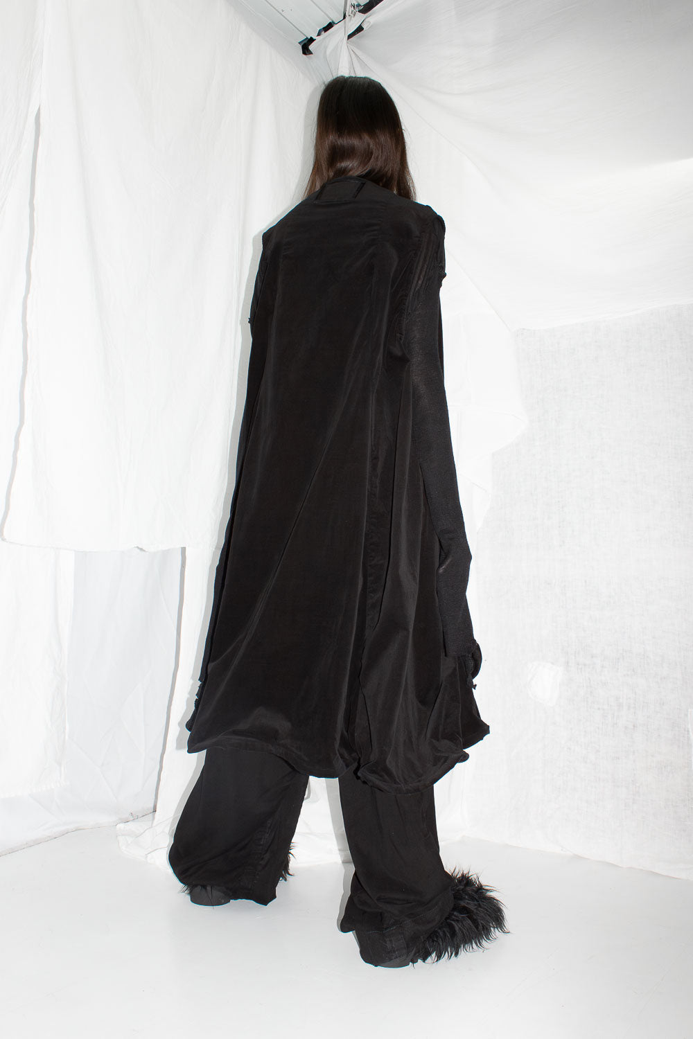 Back view of black velvet dress showing draped construction and wide hemline