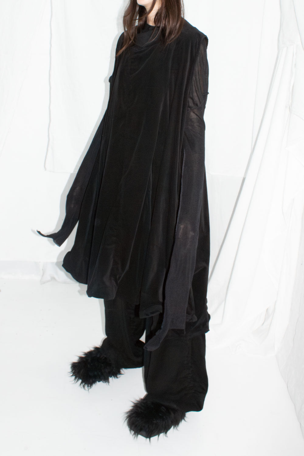 Model in black dress with arms outstretched showing full cape-like silhouette