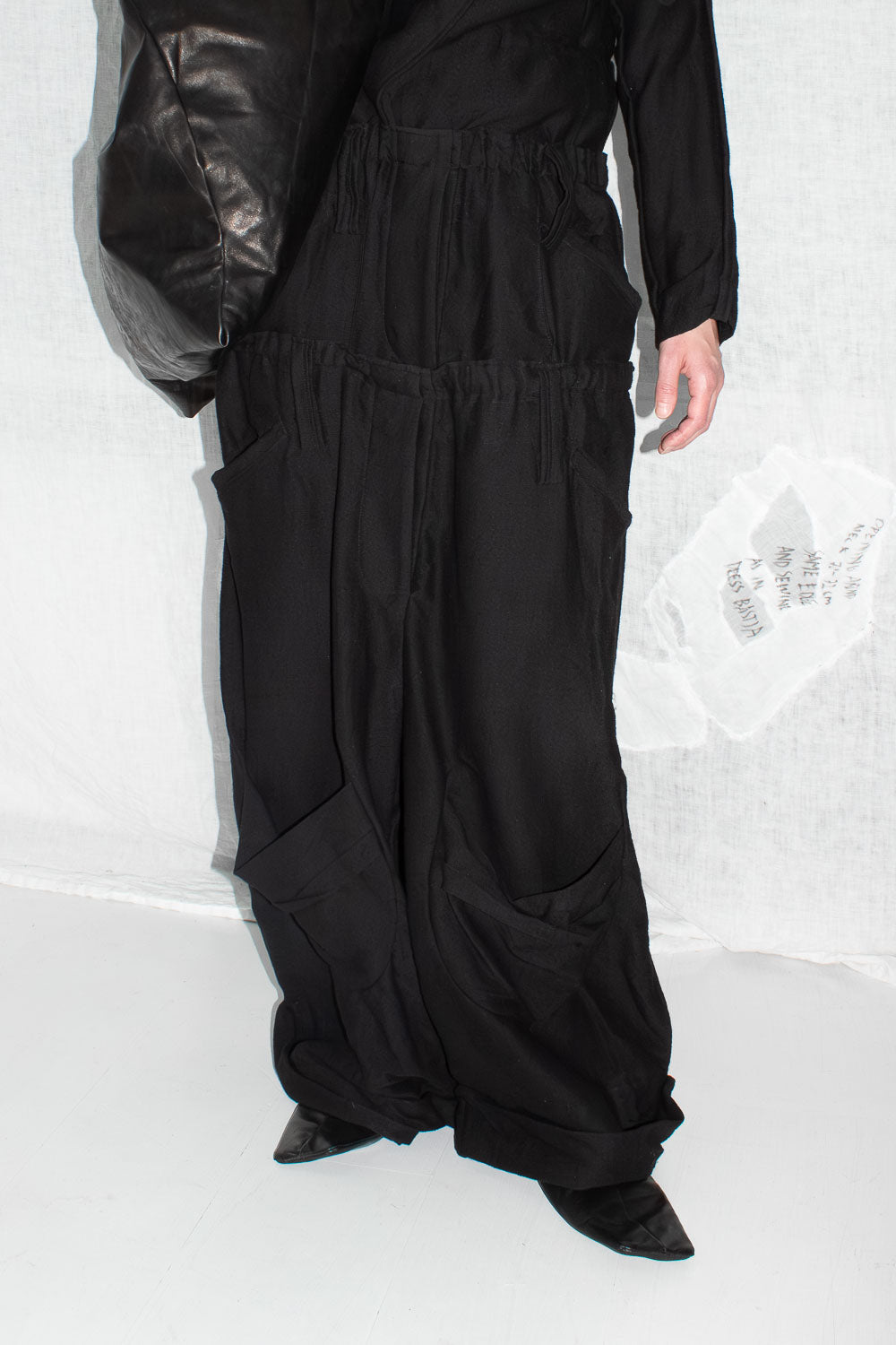 Black oversized trousers worn with leather jacket, showing full length silhouette and cargo pocket details
