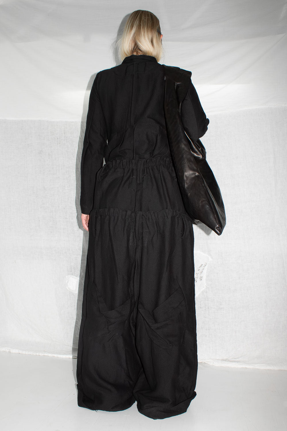 Back view of model wearing black trousers showing full length and hem construction