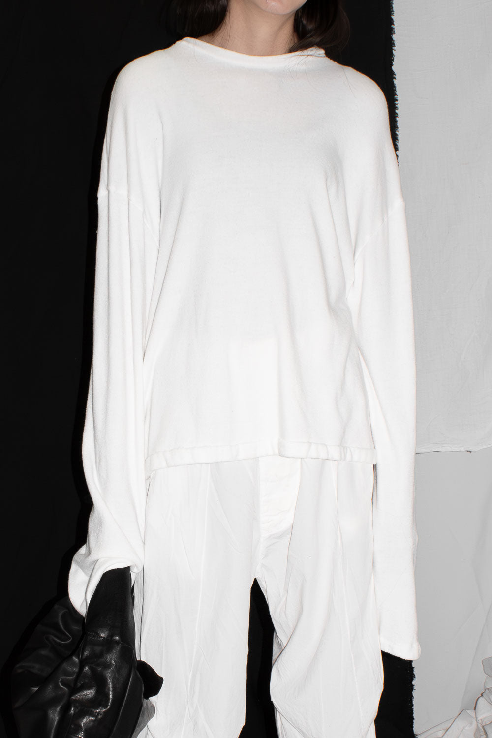 Model wearing oversized white sweater with relaxed draping and wide sleeves