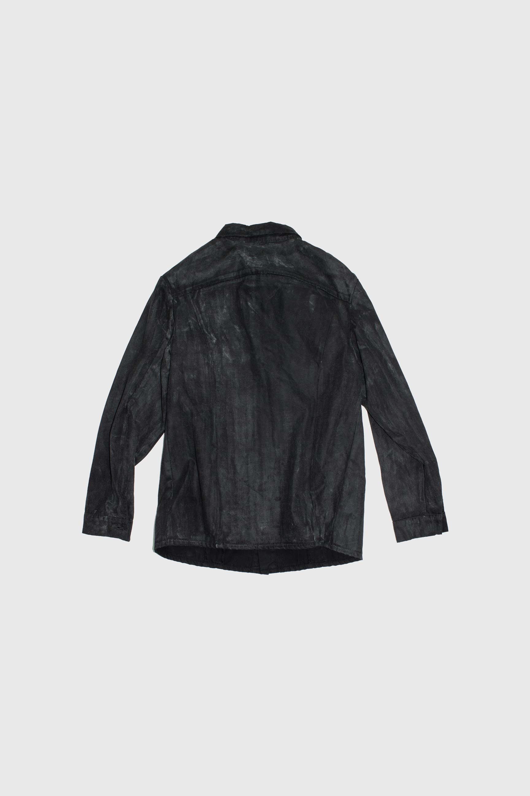 Back view of black waxed denim jacket showing yoke seaming and curved hem construction