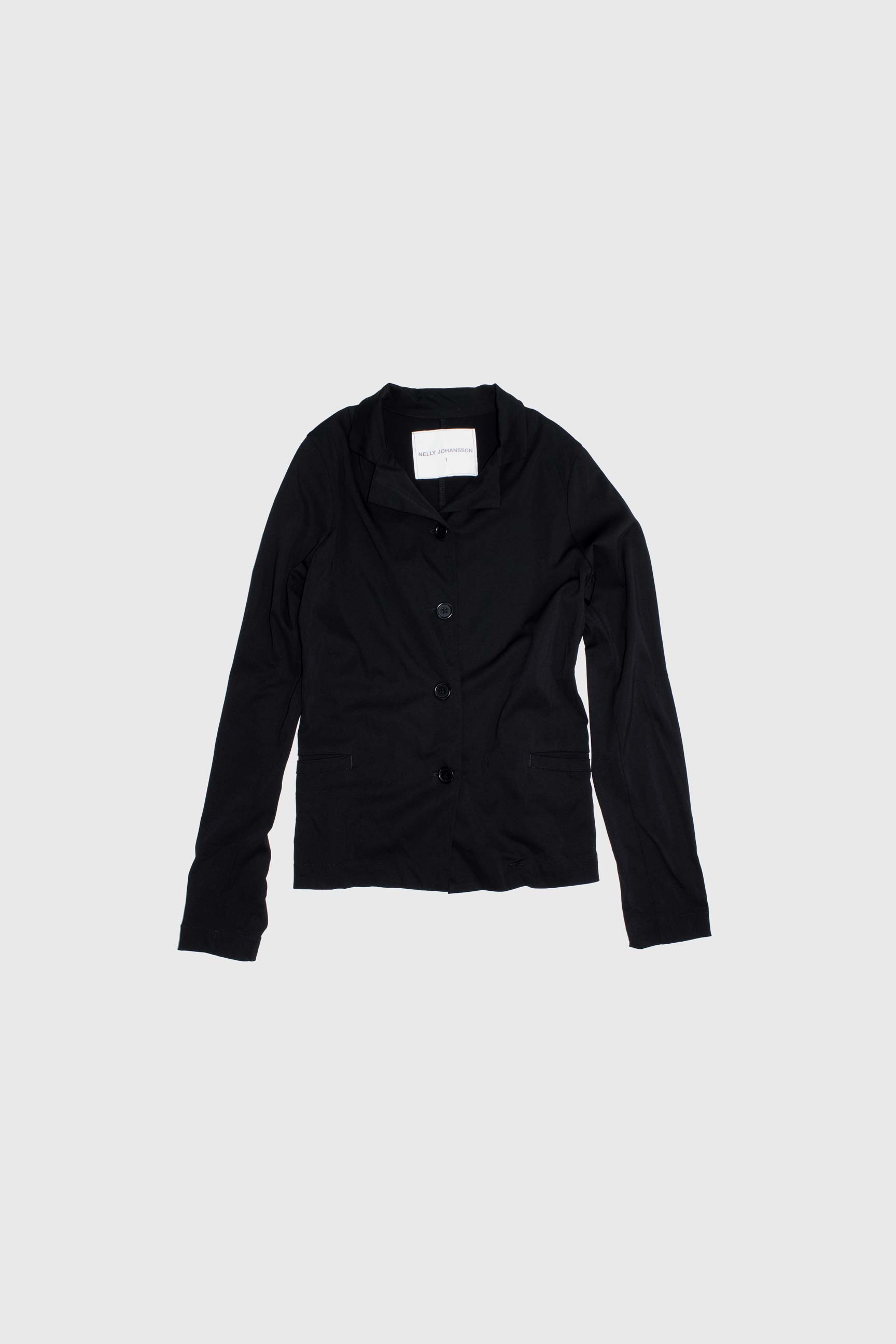 Black tailored jacket flat lay showing single-breasted construction with four buttons and asymmetrical collar