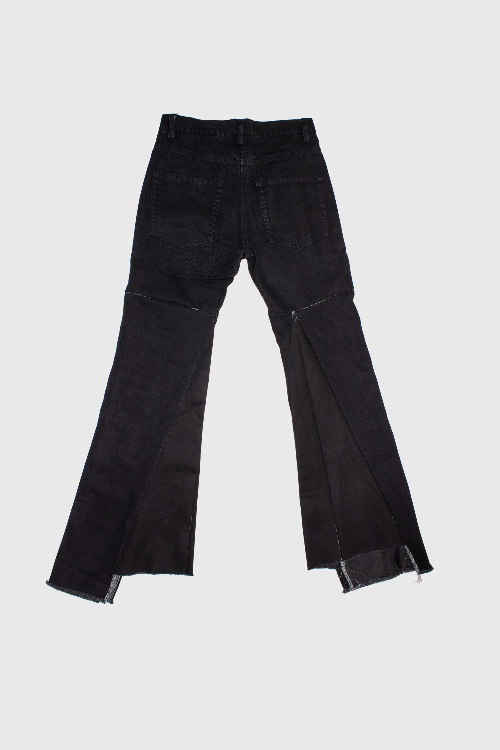 Black flared jeans laid flat showing back view with welted pockets and frayed hems