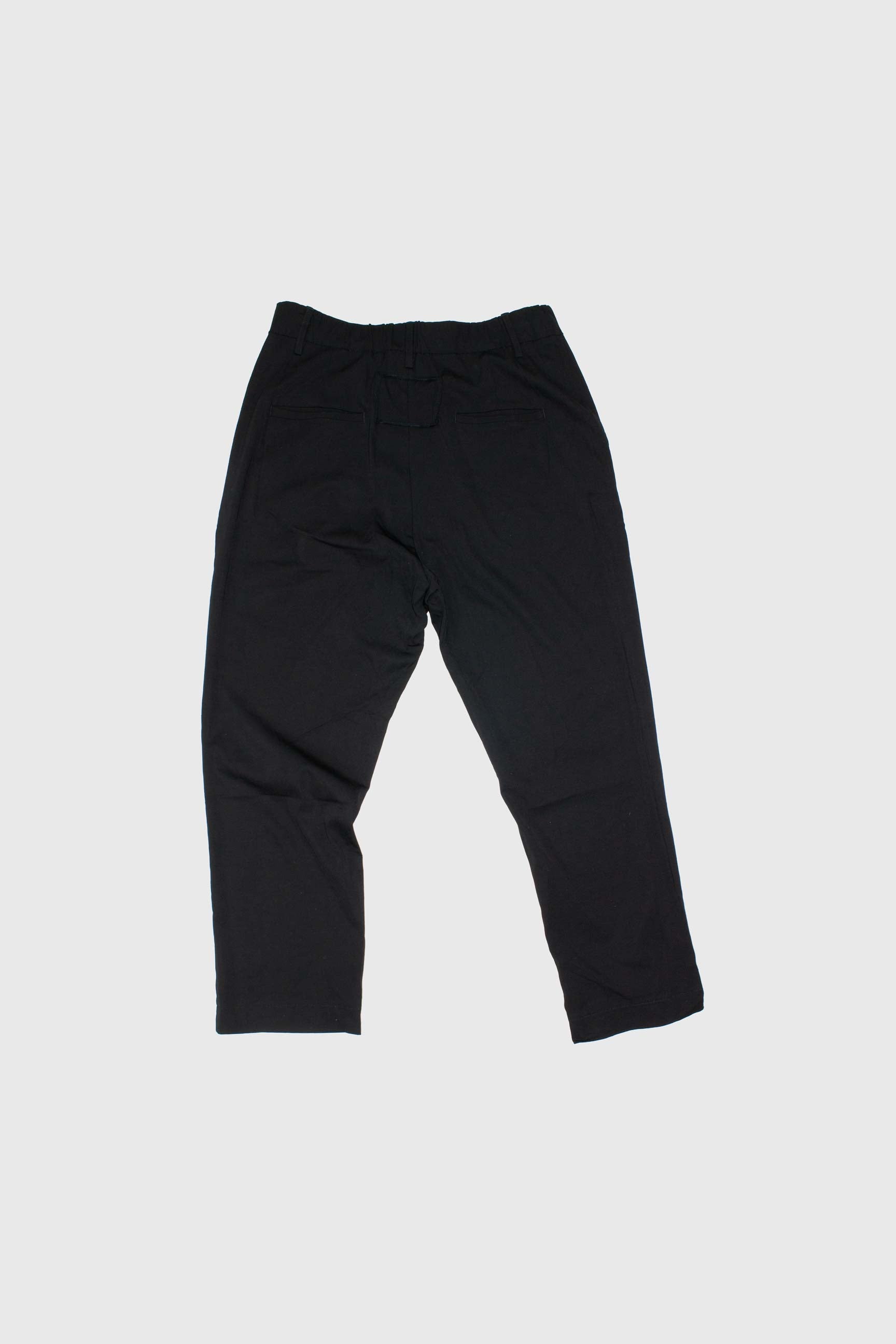 Back view of black trousers flat lay showing rear welt pockets and tapered silhouette