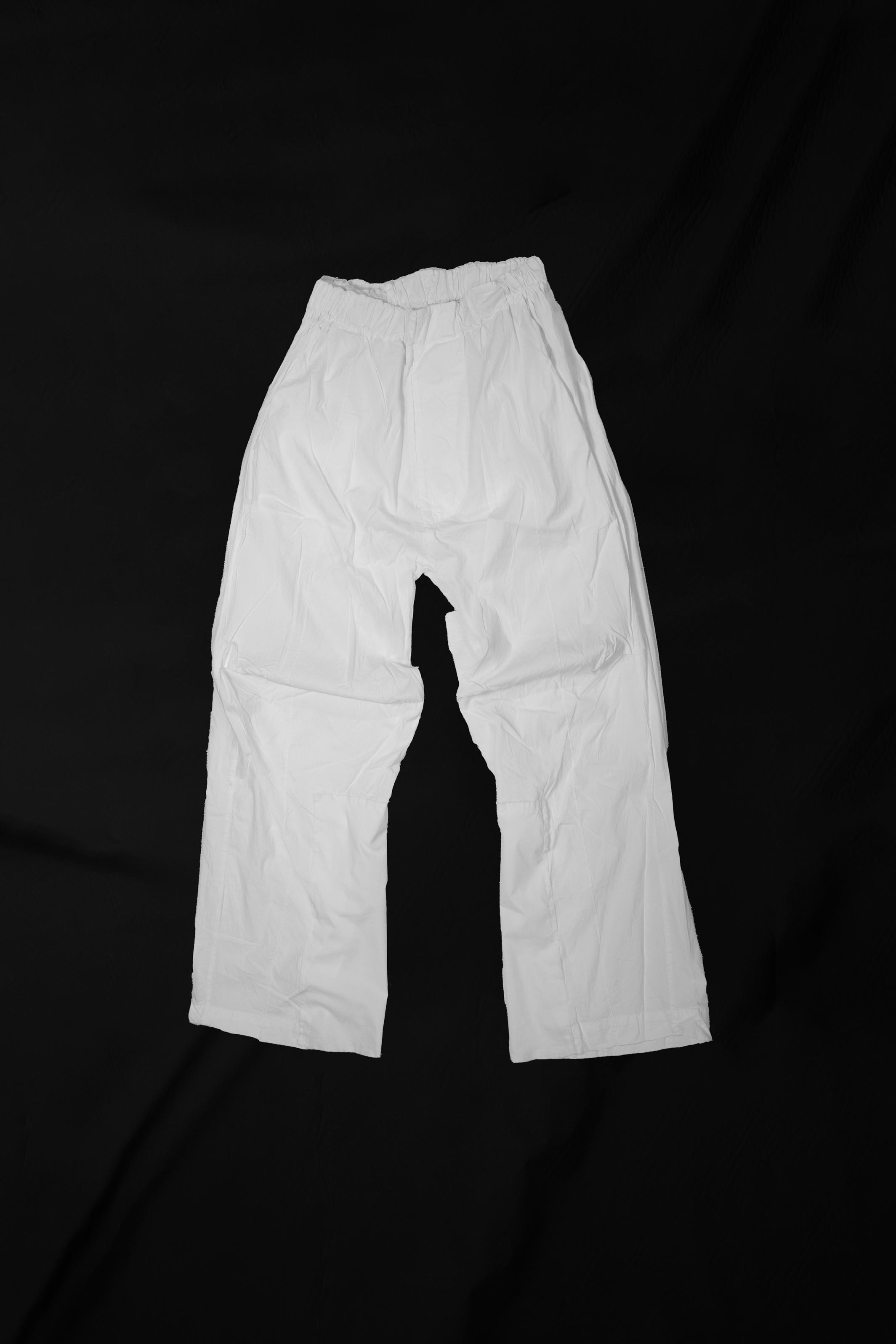 White loose slacks laid flat showing full silhouette and cropped length