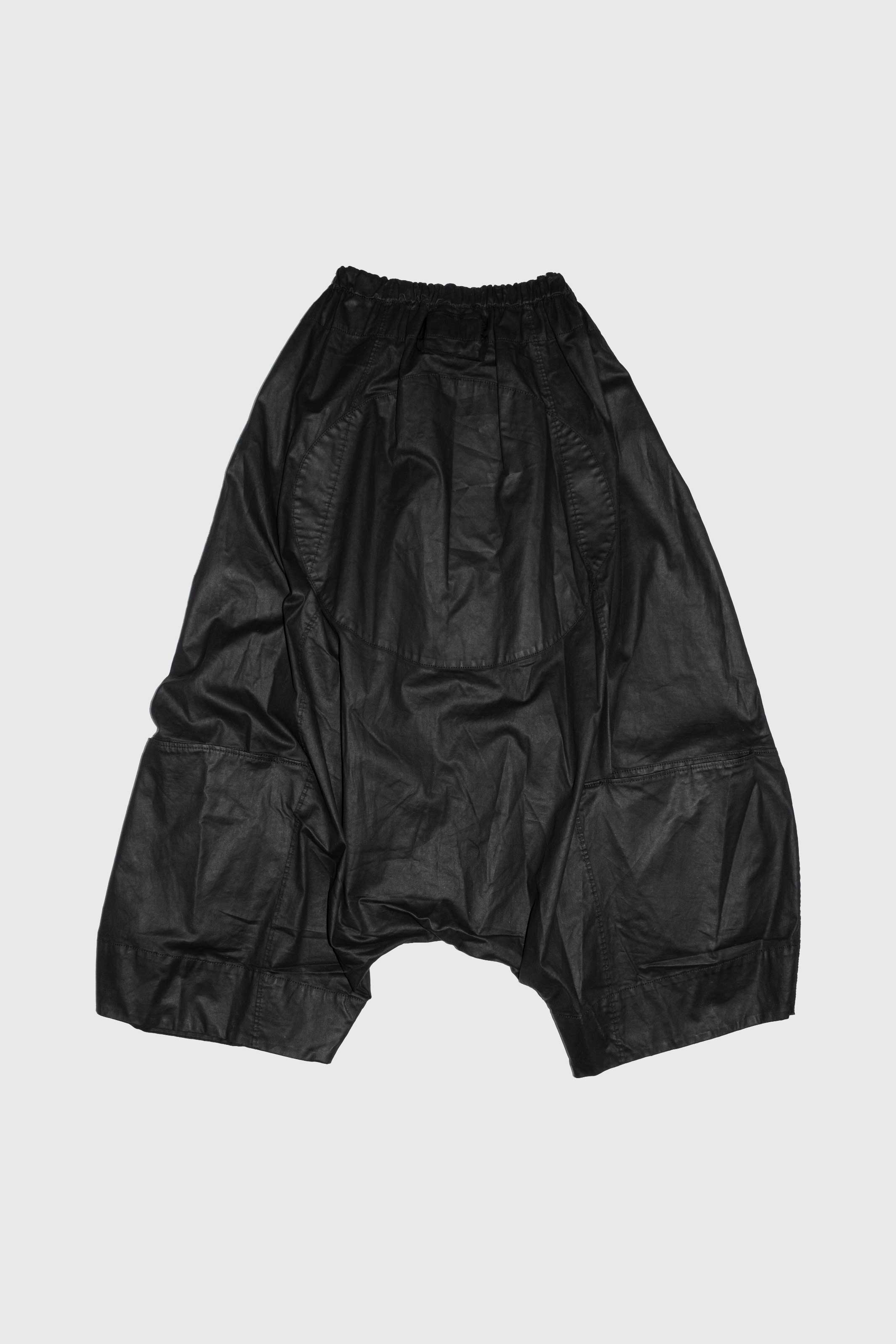Detail view of black trousers showing patch pocket construction and waxed cotton texture